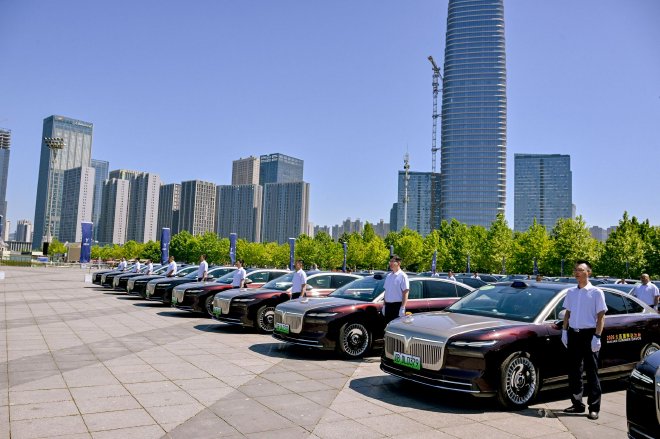 Drivers standing beside a fleet of Voyah new-energy vehicles